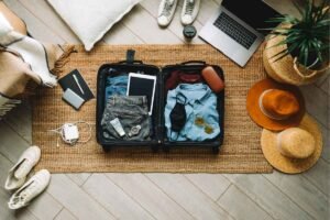 A collection of essential travel accessories, including luggage, packing organizers, a travel adapter, charger, passport holder, and neck pillow, prepared for a comfortable and convenient trip.